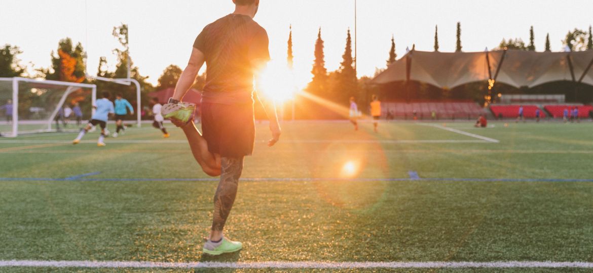 man-stretching-on-a-soccer-field-at-sunset-2022-03-06-00-18-29-utc