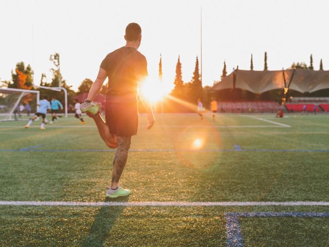 man-stretching-on-a-soccer-field-at-sunset-2022-03-06-00-18-29-utc