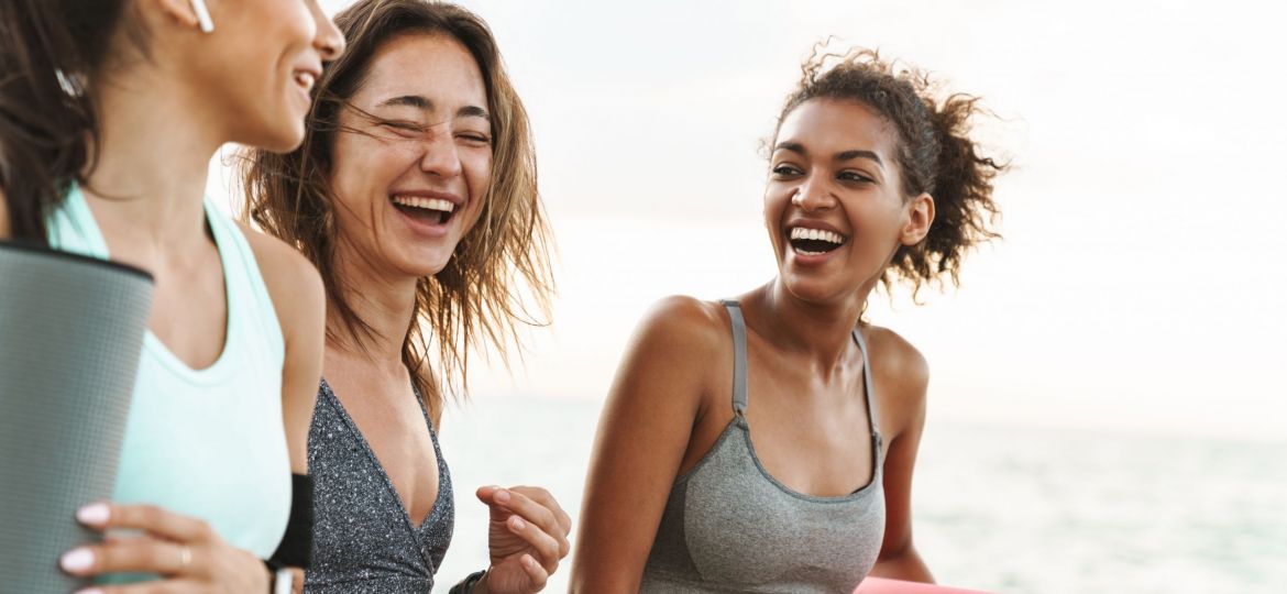 Three cheerful young sport girls standing at the beach